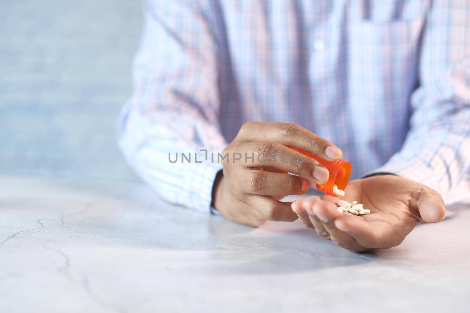 man's hand with pills spilled out of the container .
