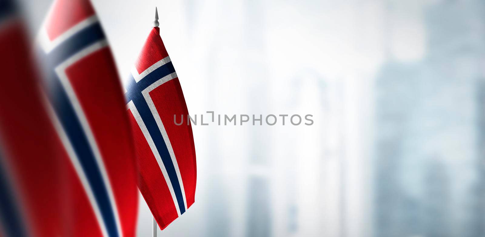 Small flags of Norway on a blurry background of the city.