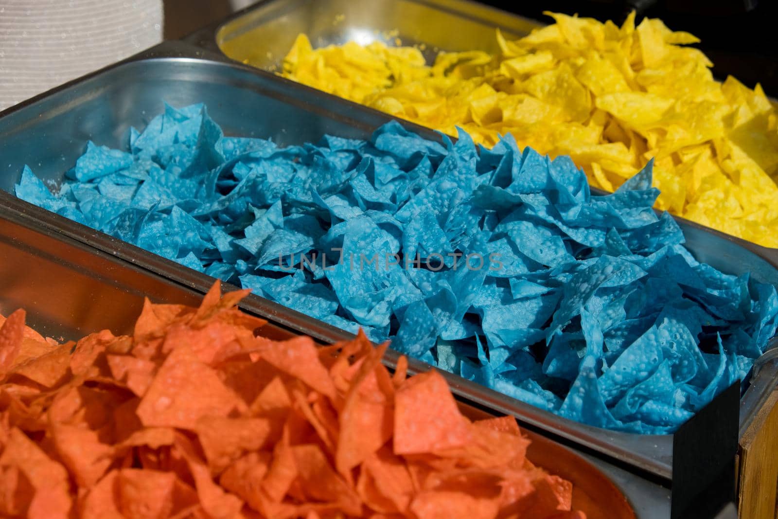 Multi colored tortilla chips in trays on the showcase. Street food festival. Selective focus. by leonik