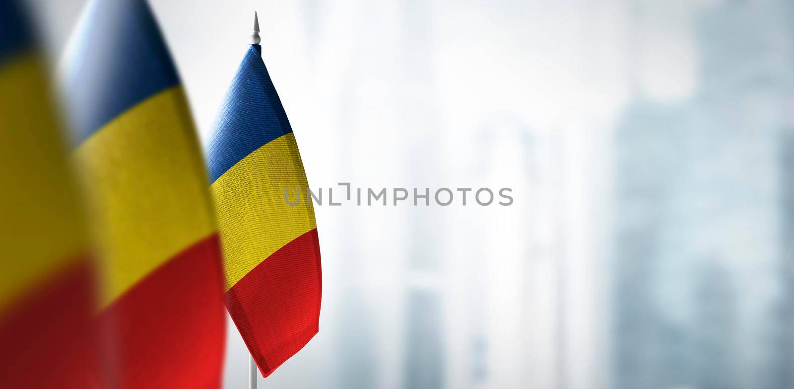 Small flags of Romania on a blurry background of the city.