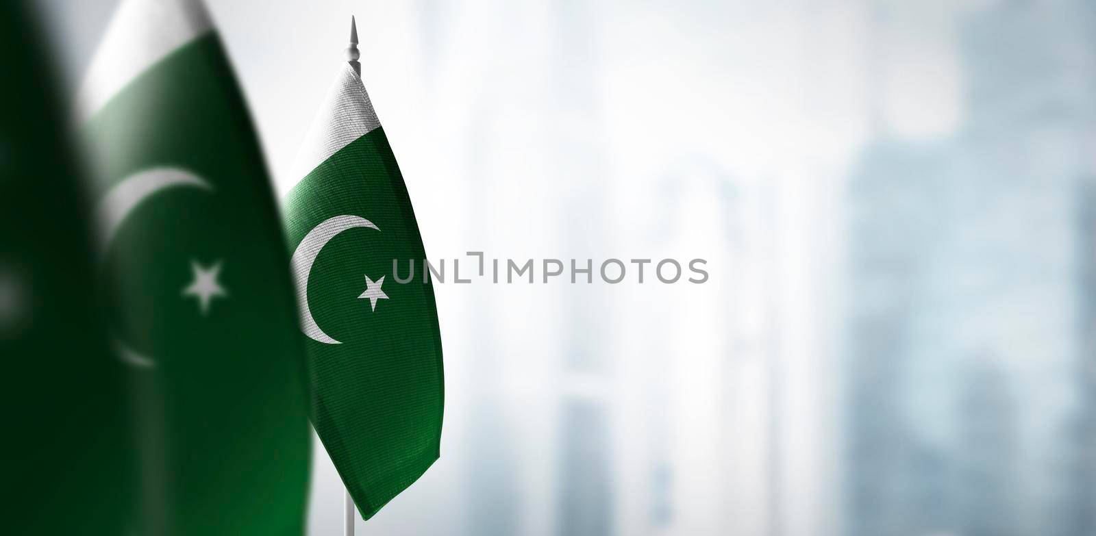 Small flags of Pakistan on a blurry background of the city.