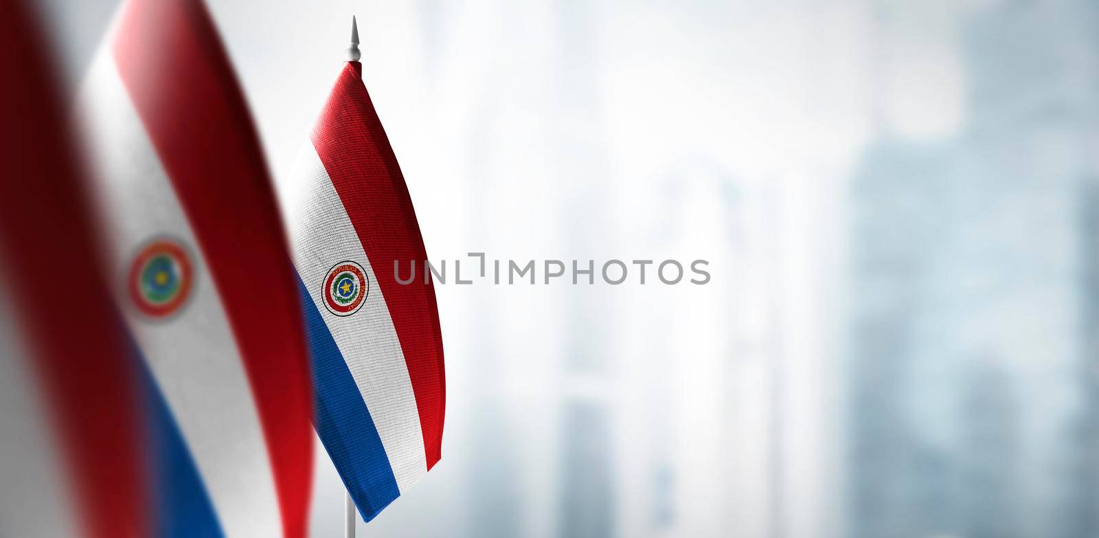 Small flags of Paraguay on a blurry background of the city by butenkow