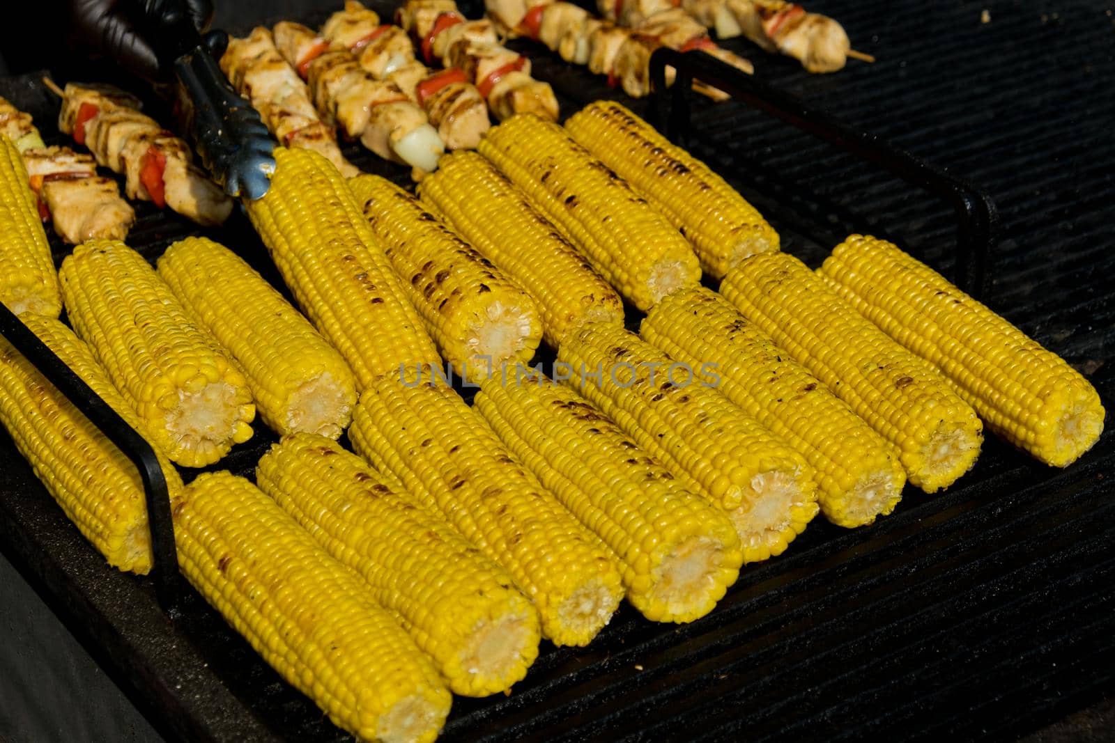 Grilling corn cob. Street food festival. Selective focus. by leonik