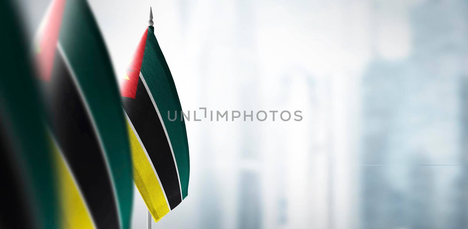 Small flags of Mozambique on a blurry background of the city.