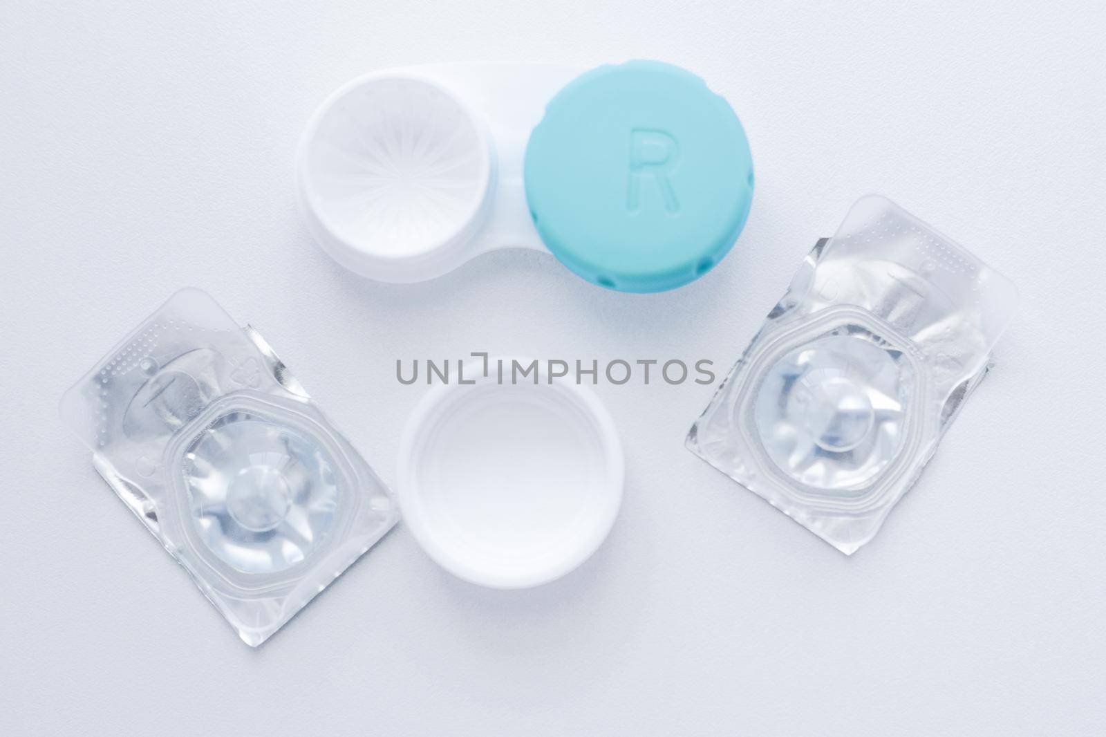 The lens container and two sealed lenses lie in the center on a white background. top view, flat lay, copy space, isolate. High quality photo