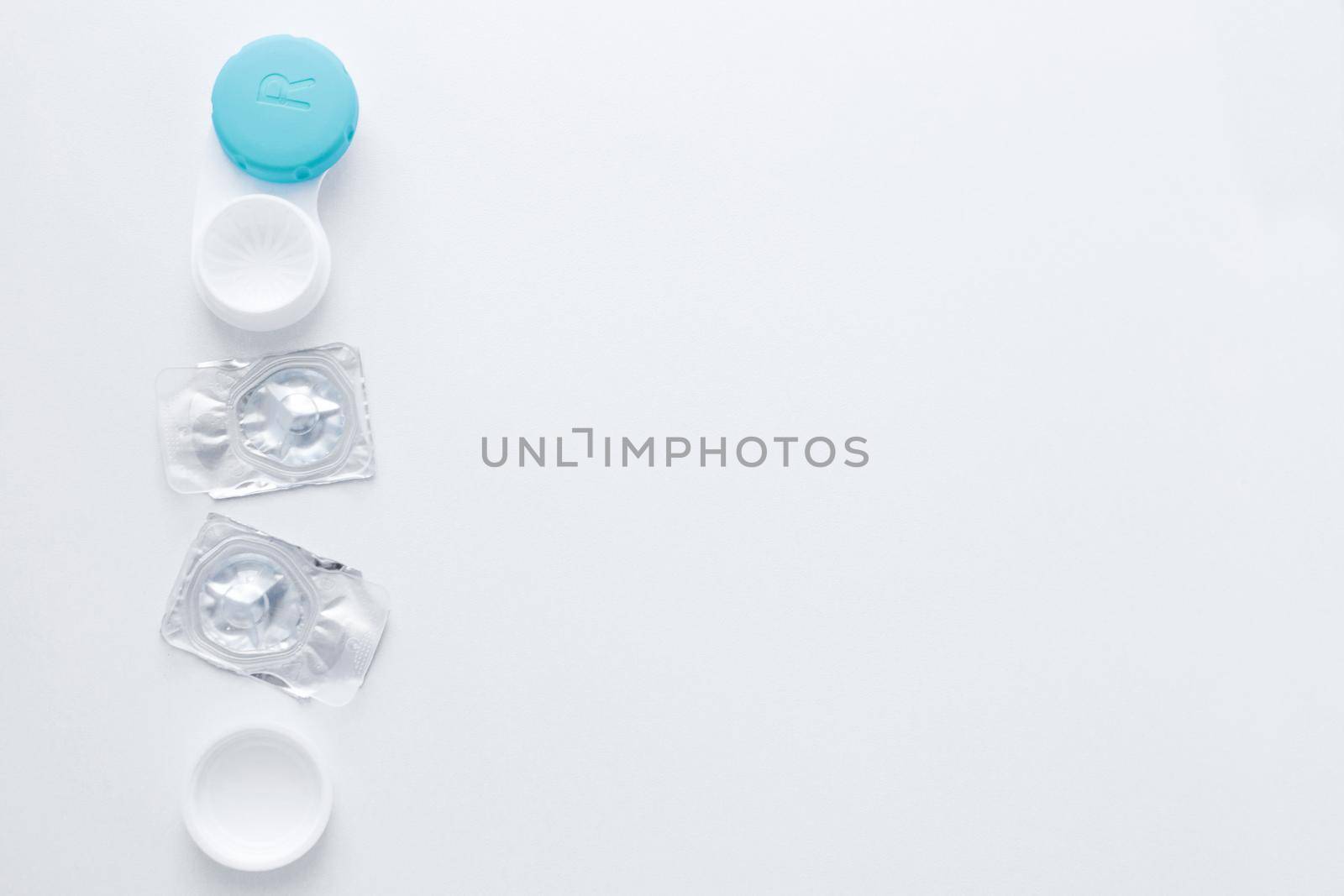 A container for lenses and two sealed lenses lie on the side on a white background with space for text.top view, flat lay, copy space, isolate. High quality photo