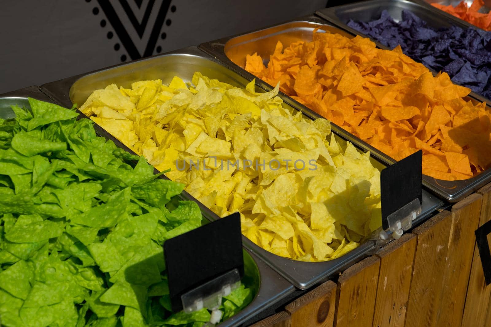 Multi colored tortilla chips in trays on the showcase. Street food festival. Selective focus.