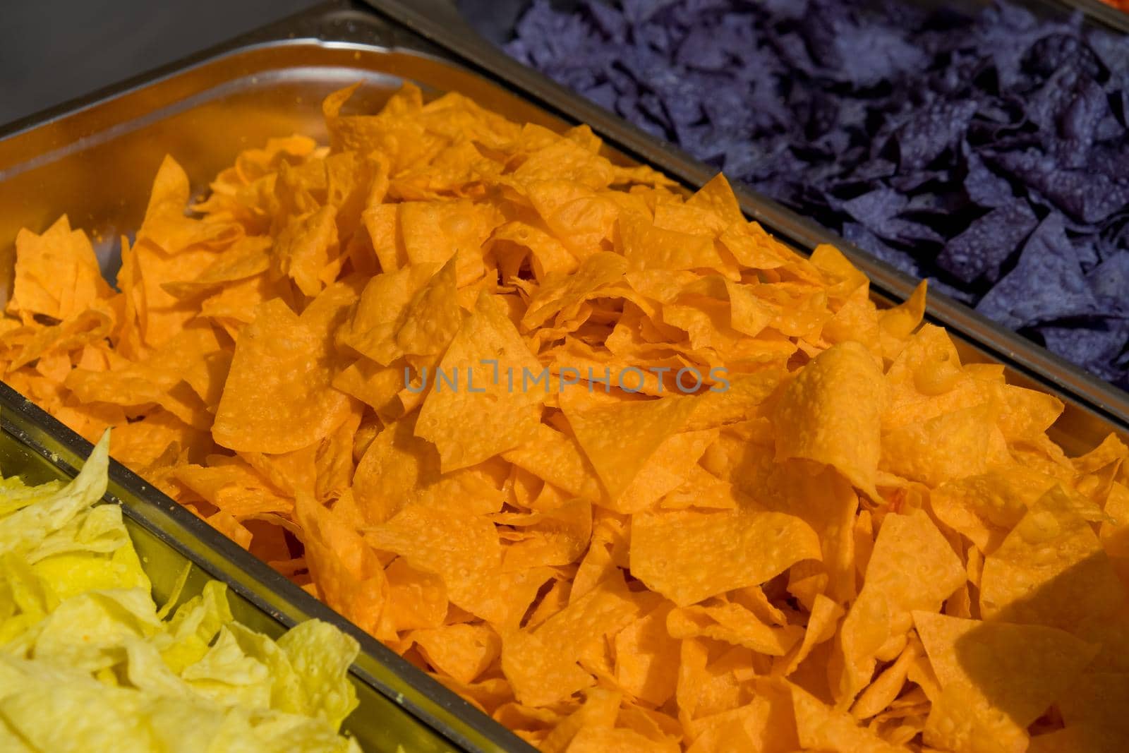 Multi colored tortilla chips in trays on the showcase. Street food festival. Selective focus.