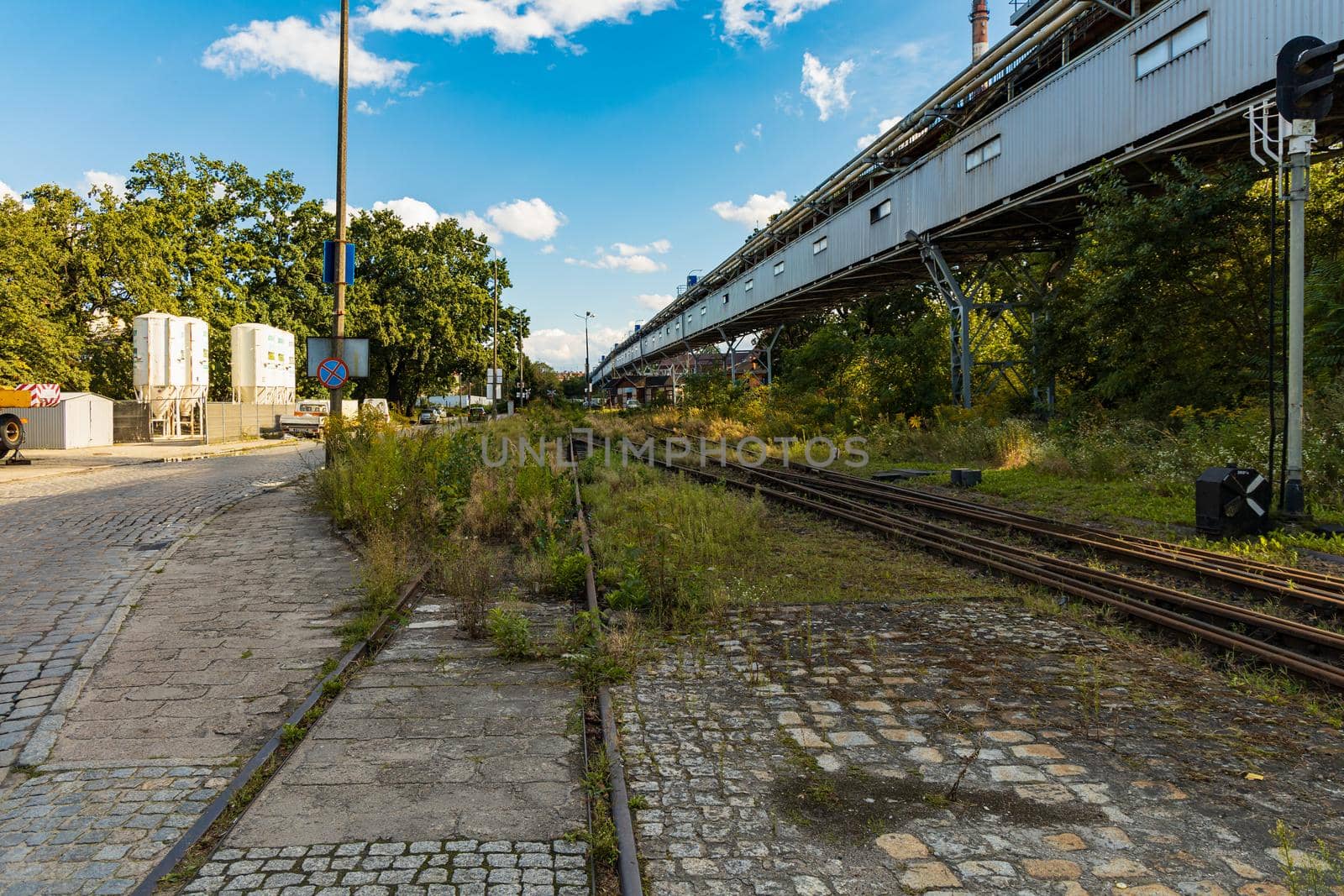 Long rails at old unused factory square next to long bridge by Wierzchu