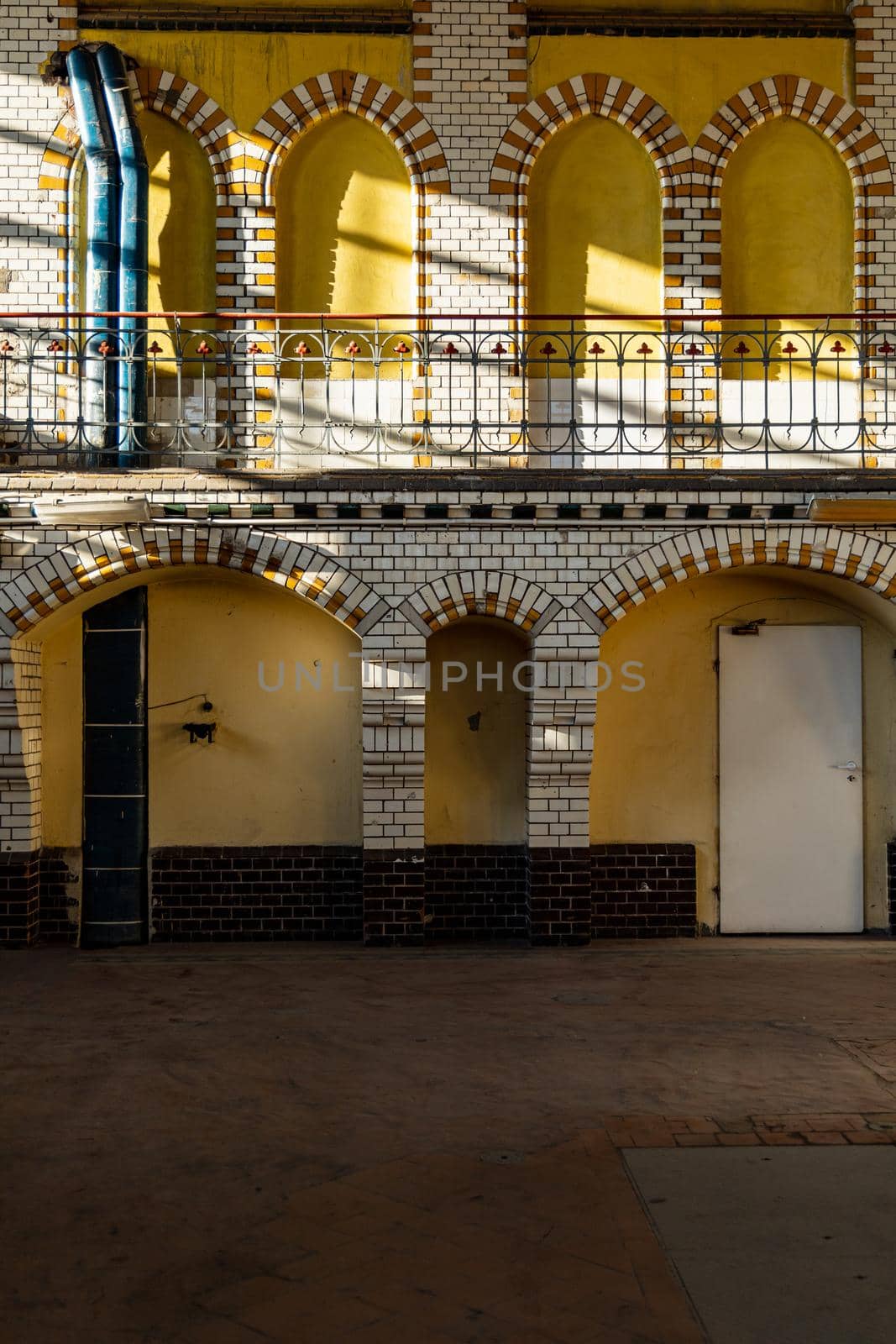 Yellow wall full of arcs made of red and white tiles and balcony inside pumping station by Wierzchu