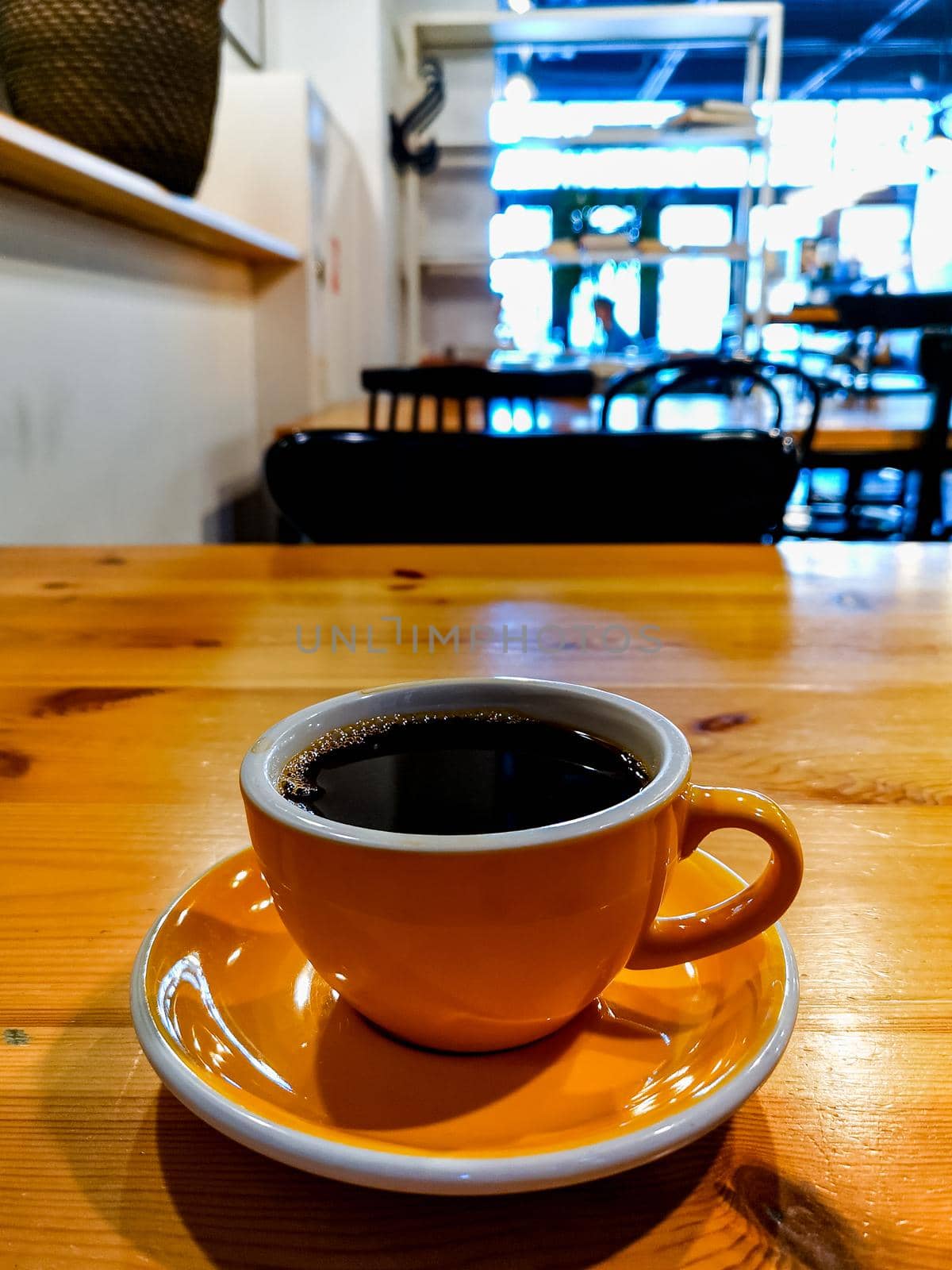 Yellow cup of black overflow coffee in small cafe by Wierzchu