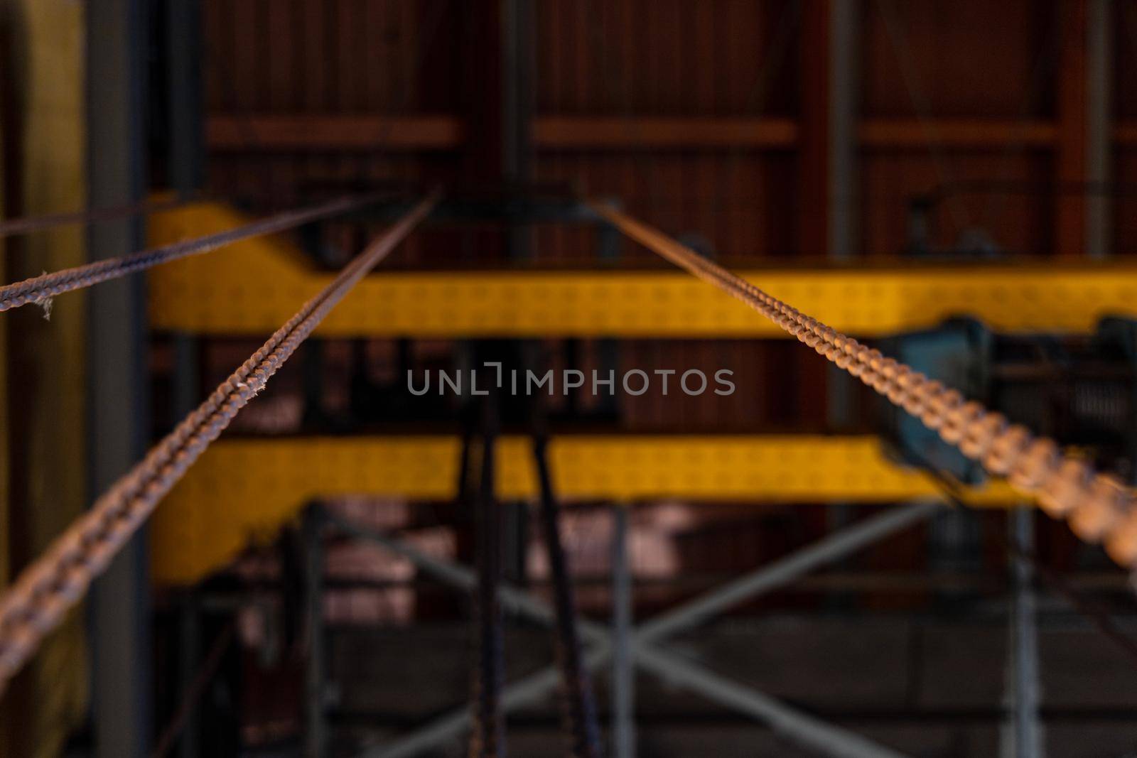 Upward view to long steel chains hanged on steel constructions