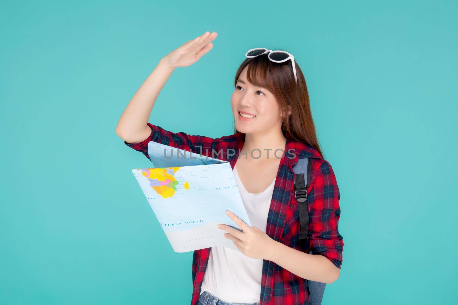 Beautiful happy young asian woman travel holding and looking a paper map isolated on blue background, asia girl search journey with direction in vacation trip with cheerful for leisure. by nnudoo