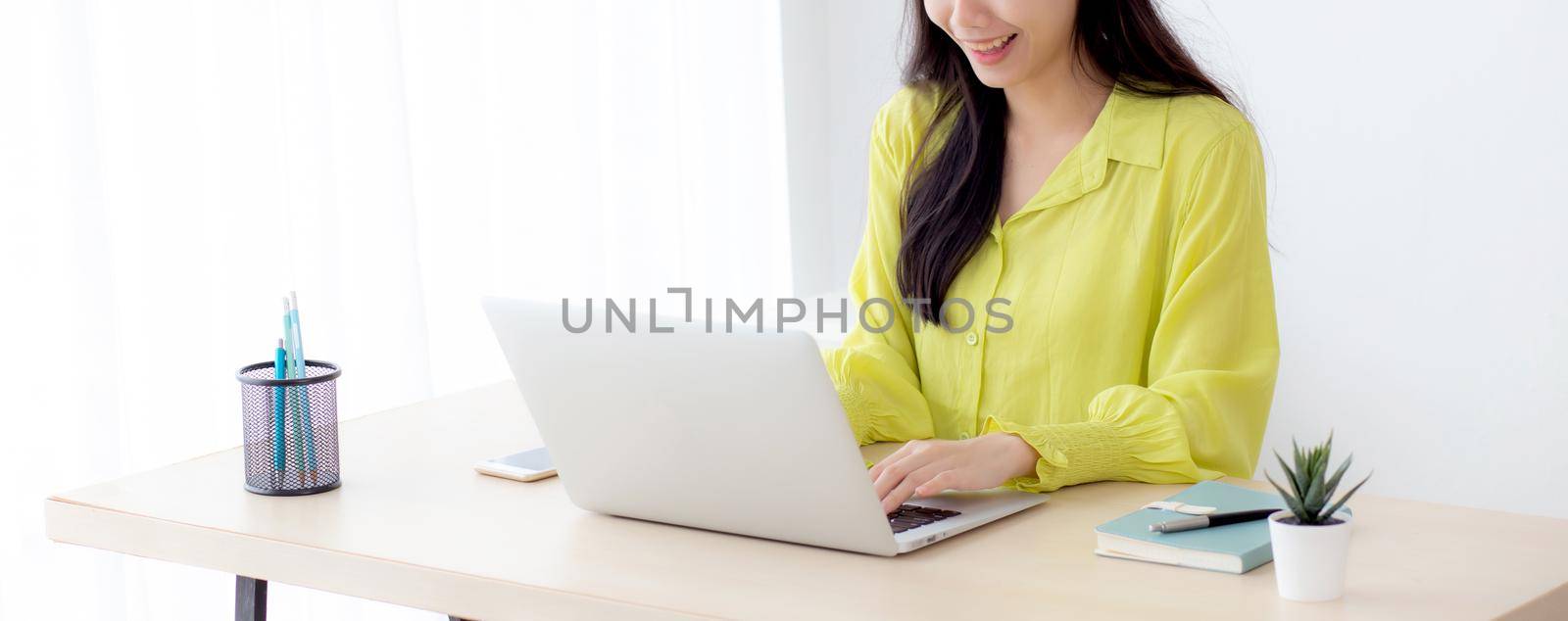 Young asian businesswoman working on laptop computer on desk at home office, freelance looking and typing on notebook on table, lifestyle of woman studying online, business and education concept.