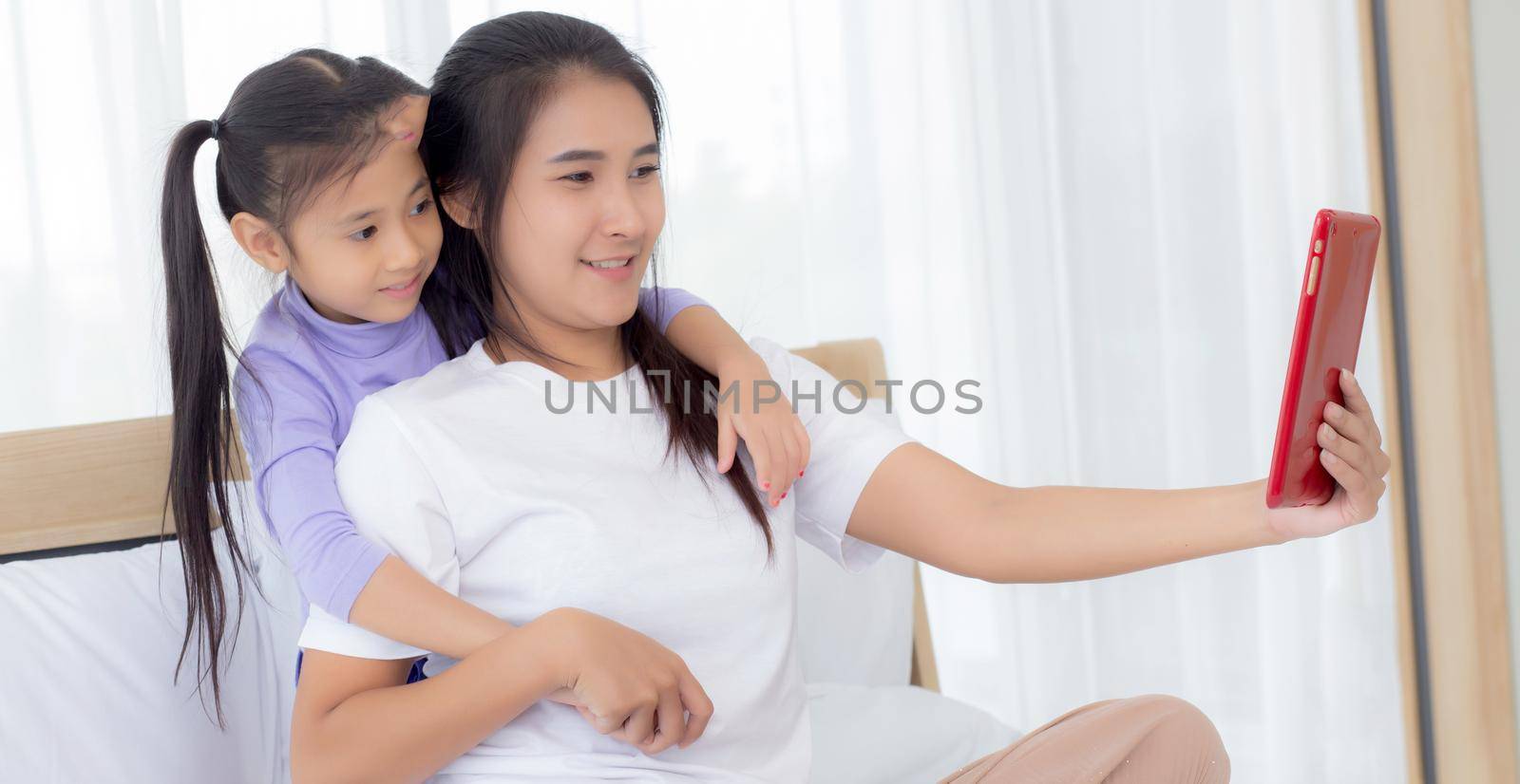 Young asian mom and daughter video call on tablet computer greeting with family together, happy mother and girl with relationship using technology in communication to internet online, two people.
