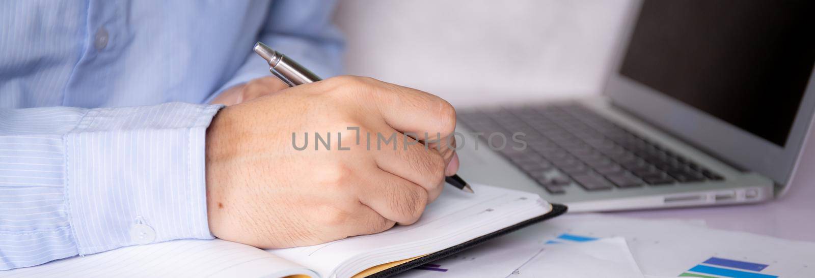 Hands of businessman calculate tax with calculator while laptop computer on desk, man planning finance and investment with graph and chart, statistic and examining account, business concept. by nnudoo