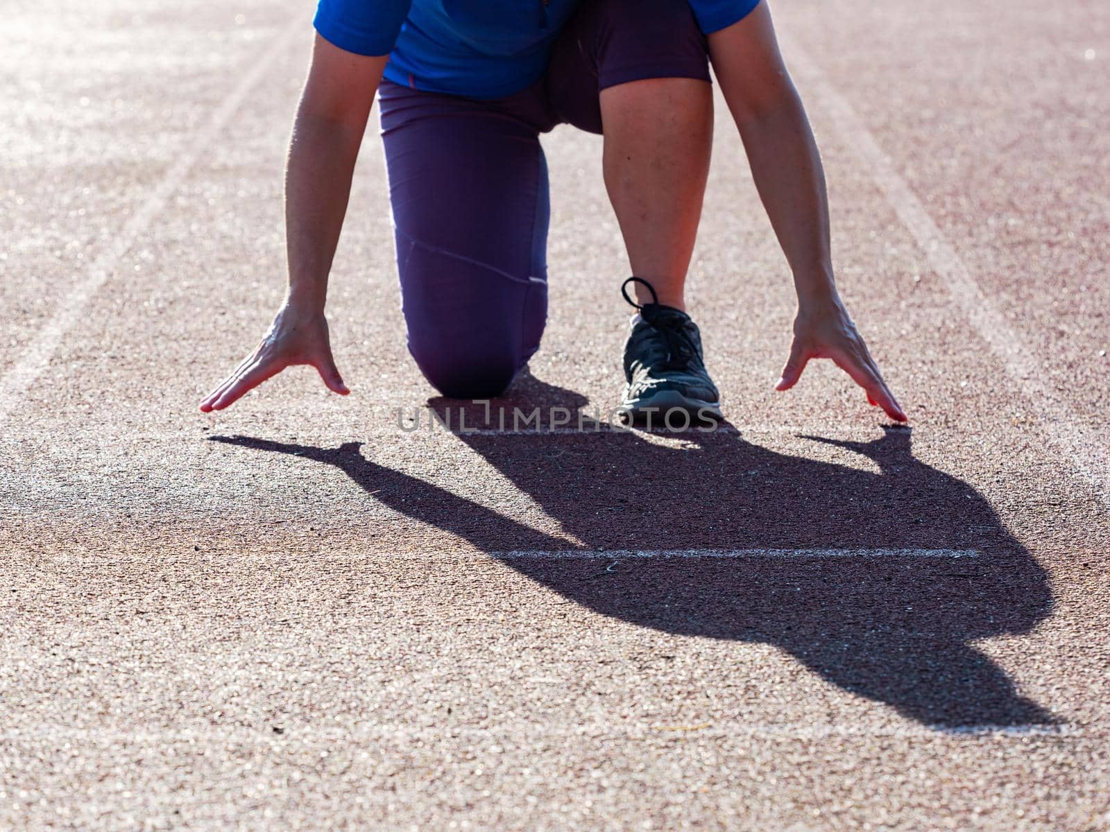 Woman on the athletics track exercises in the position of the start 