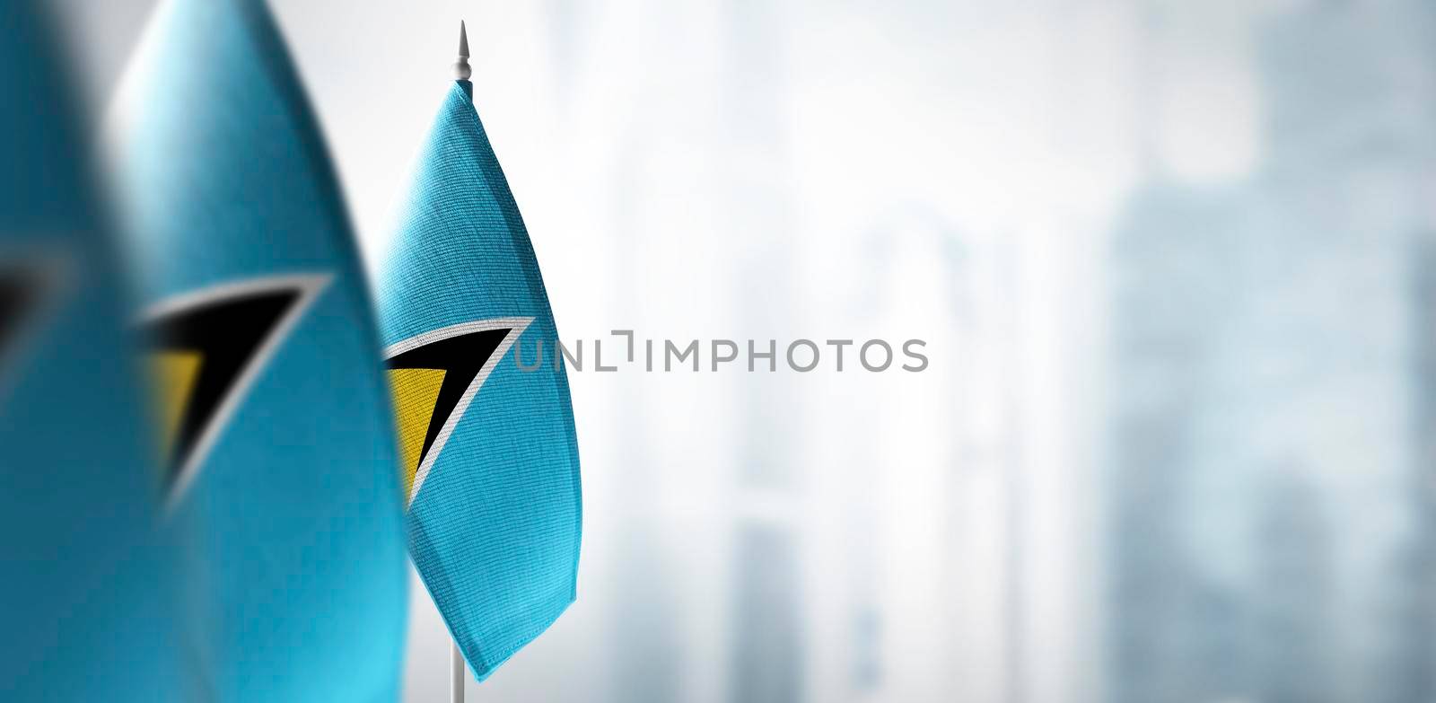 Small flags of Saint Lucia on a blurry background of the city.