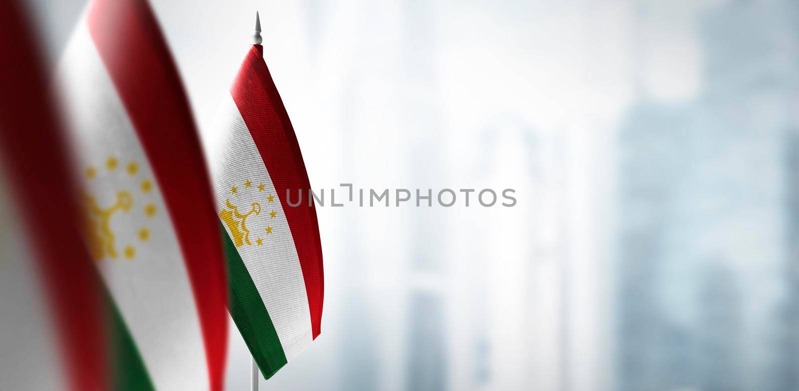 Small flags of Tajikistan on a blurry background of the city by butenkow