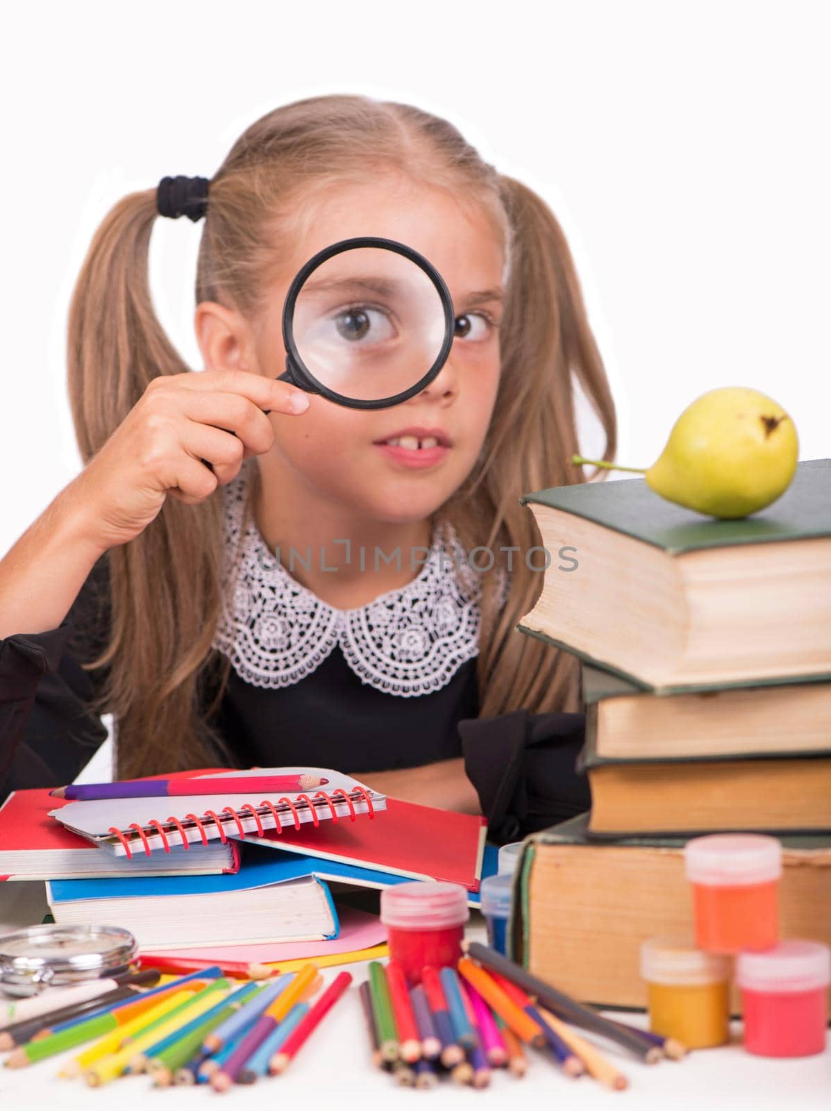 Girl is looking at books through magnifier, isolated over white