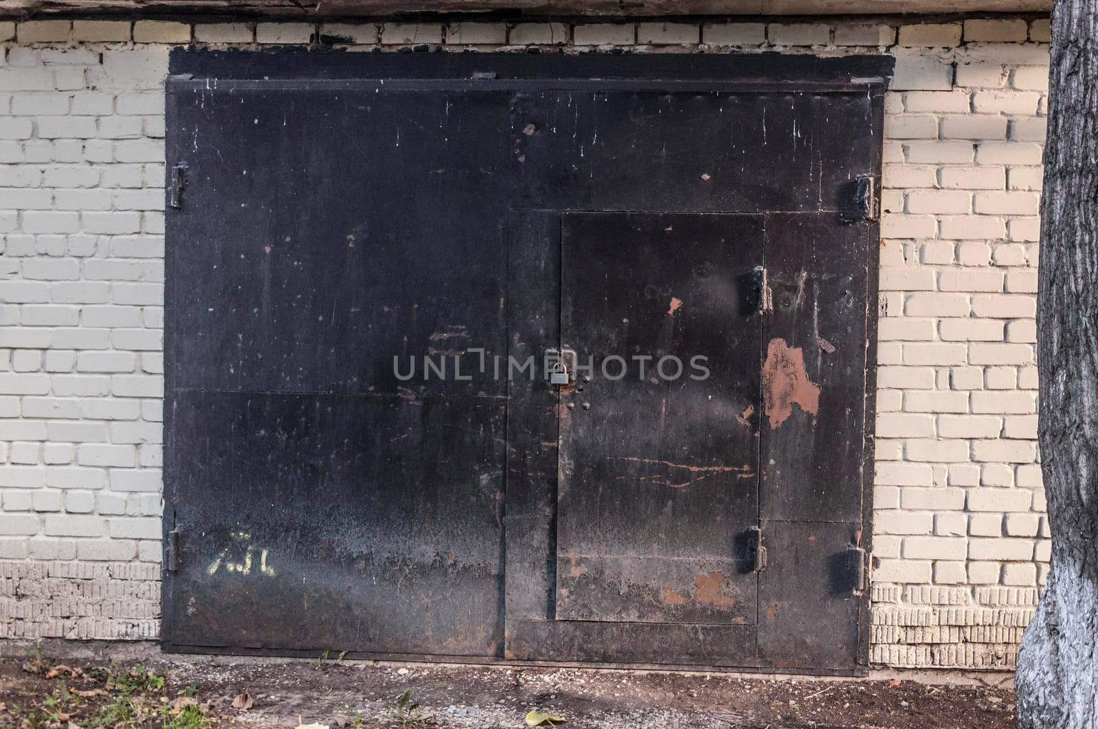 Black metal garage gate in white brick wall, background photo texture