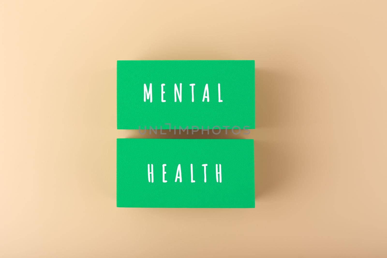 Mental health text written on green blocks on bright beige background by Senorina_Irina