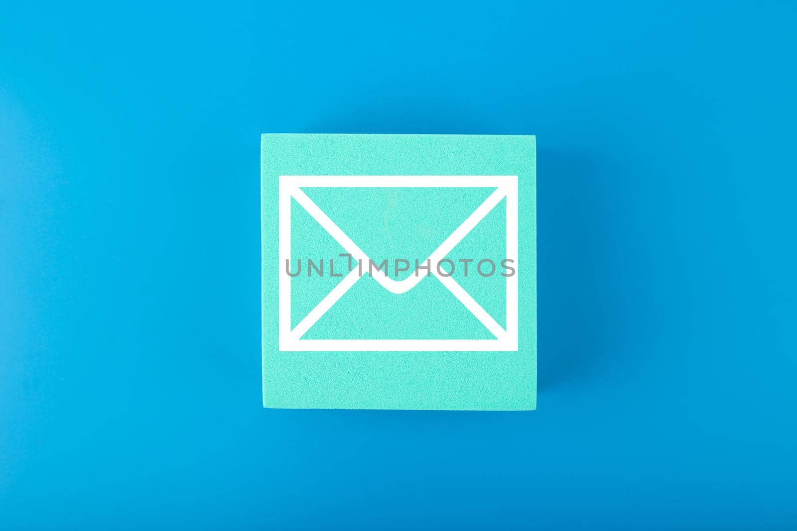 Email marketing, newsletter, promotion information and virtual communication concept. Envelope drawn on toy square against blue background. 