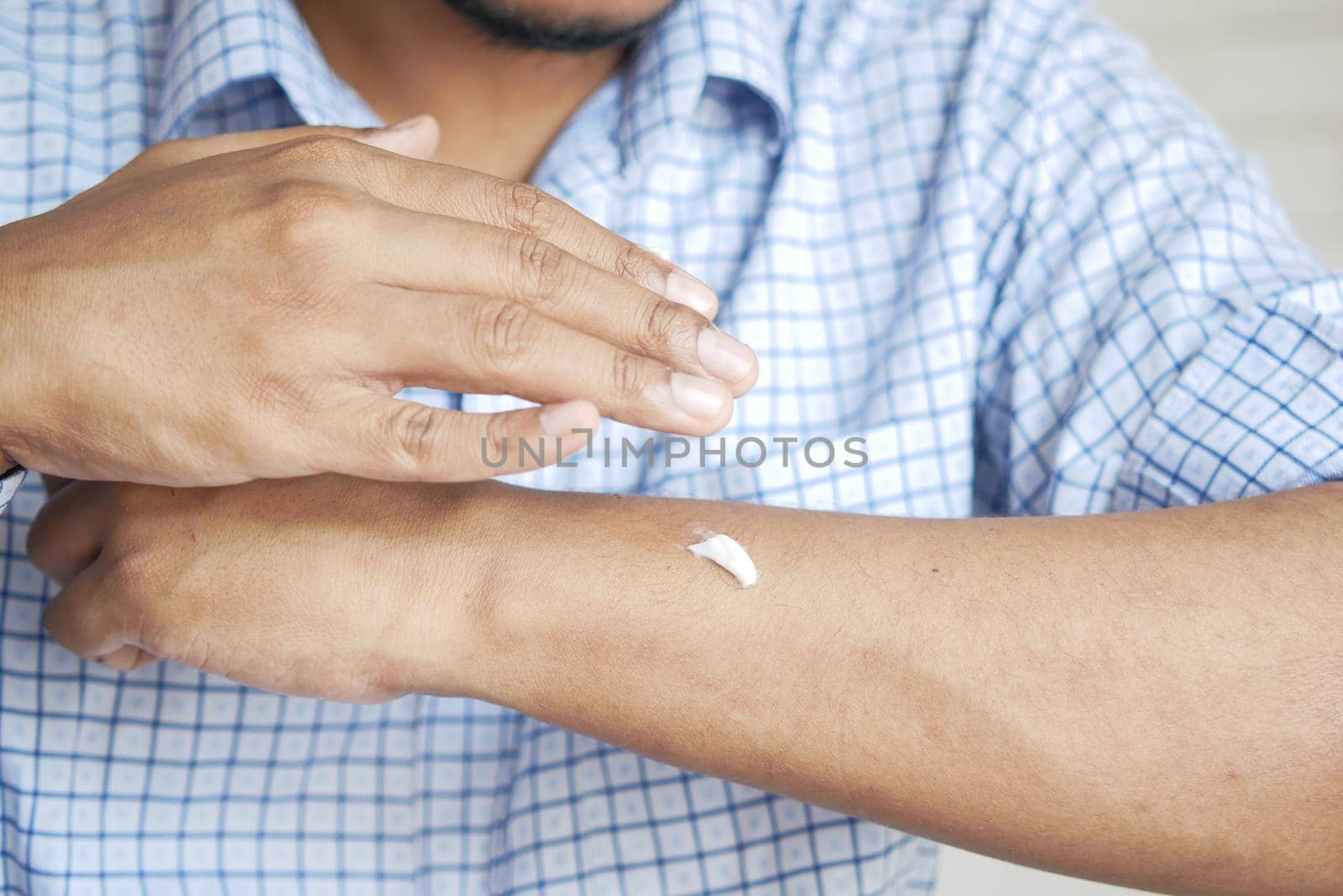 man applying beauty cream onto skin .