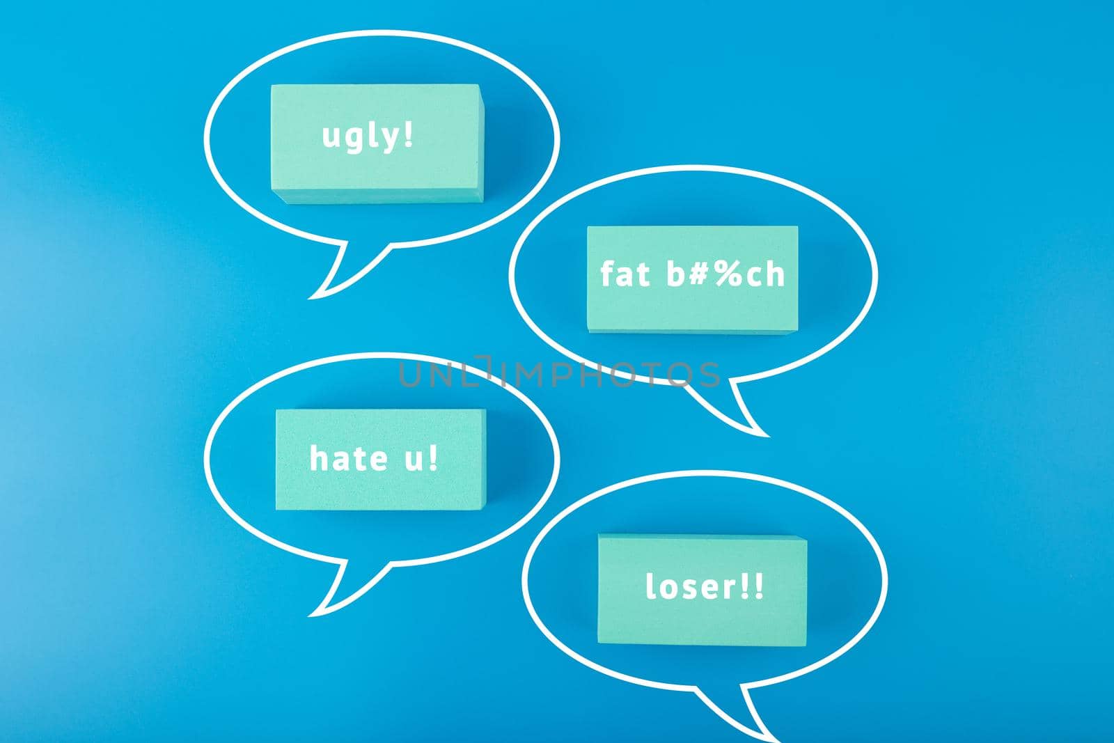 Creative cyberbullying concept. Minimal flat lay with negative, insulting messages in speech bubbles on blue background. 