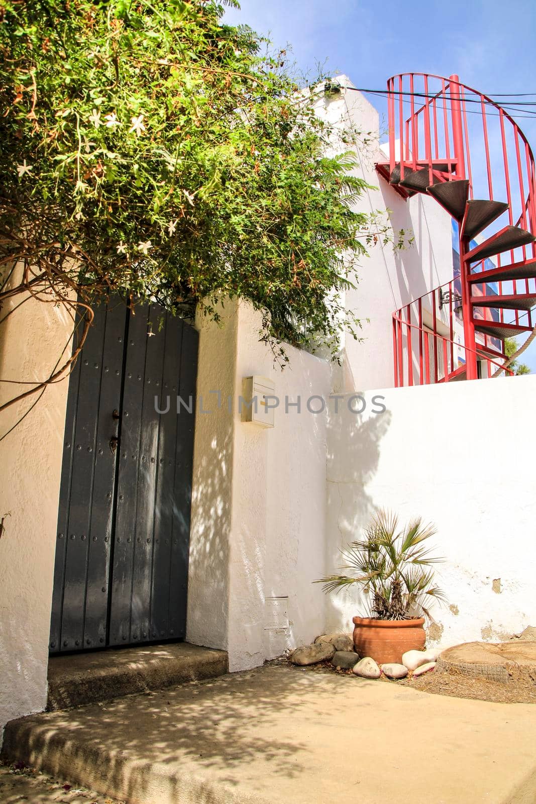 Typical Andalusian whitewashed facade with gray painted door and red staircase