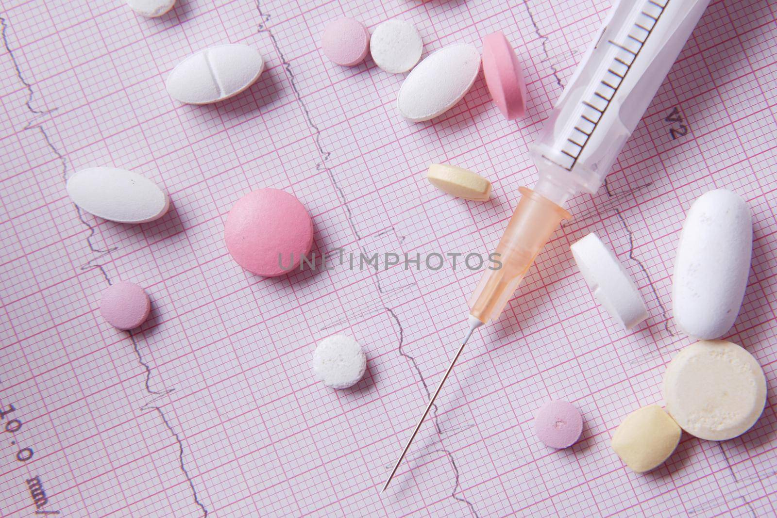 stethoscope, medical pill and syringe on a cardio diagram