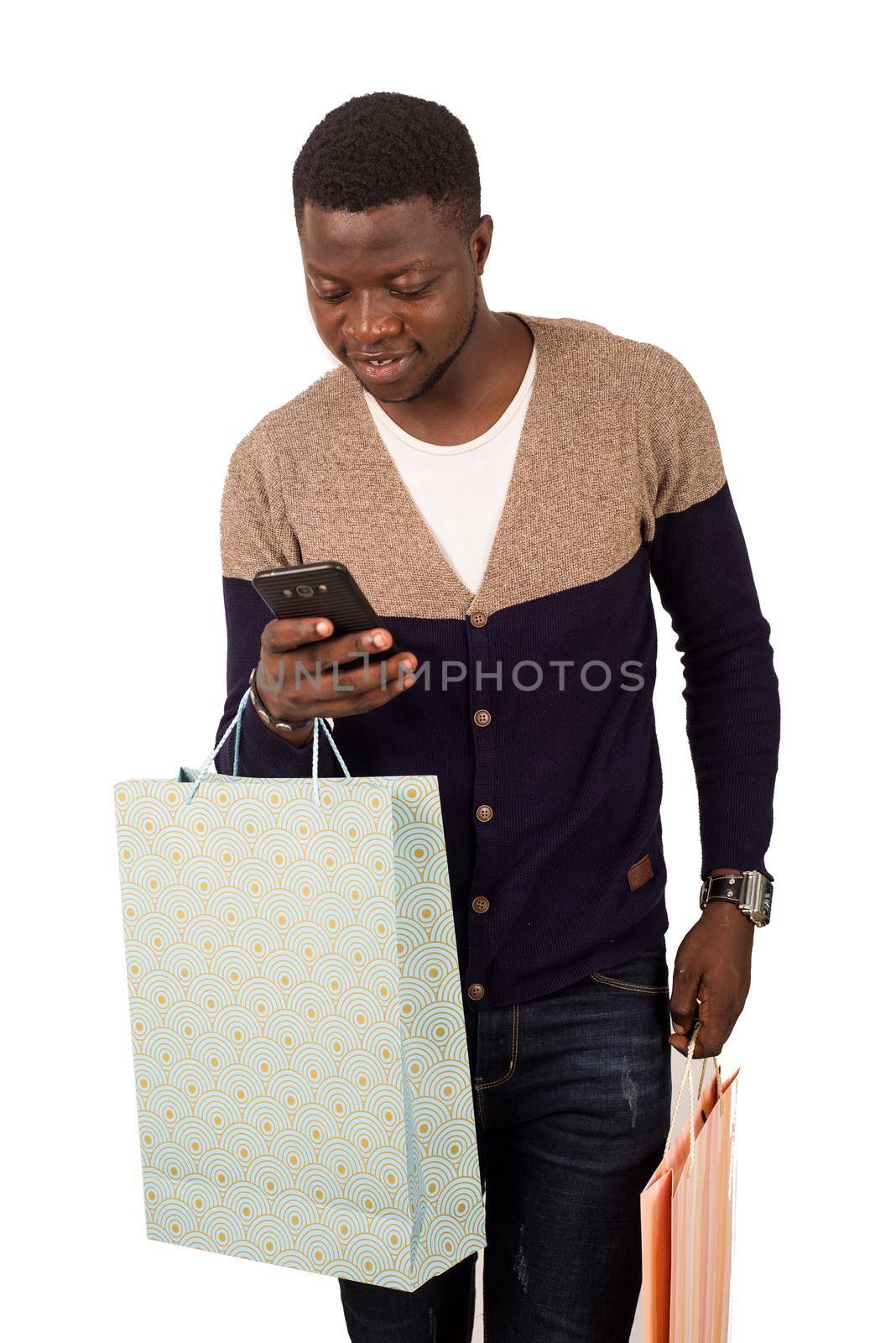 young smiling man with shopping bags is using a mobile phone by vystek
