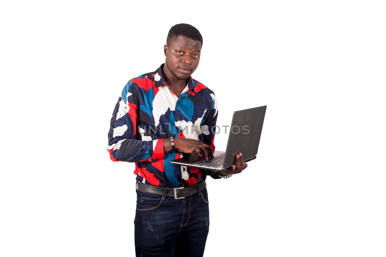 young african man standing on white background with laptop watching the camera.