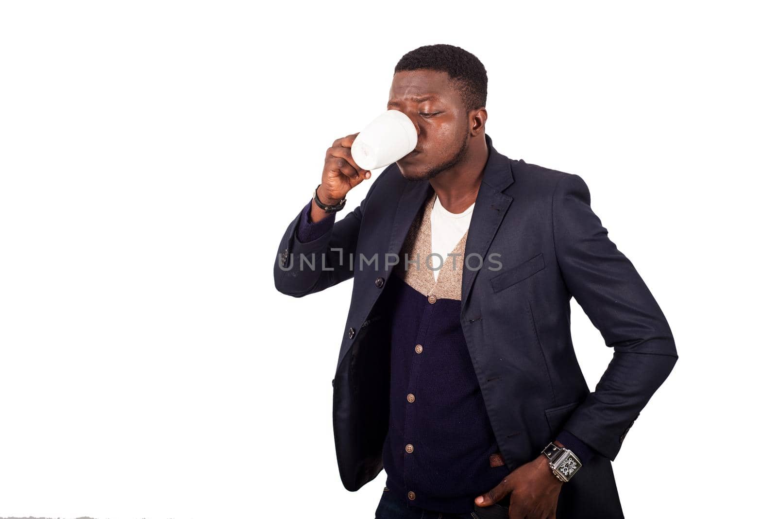 young man standing on white background in jacket hand in pocket drinking coffee.