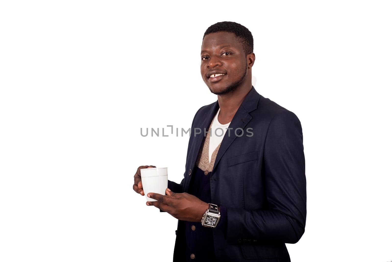 young man standing on white background in jacket holding cup in hand watching the camera smiling.