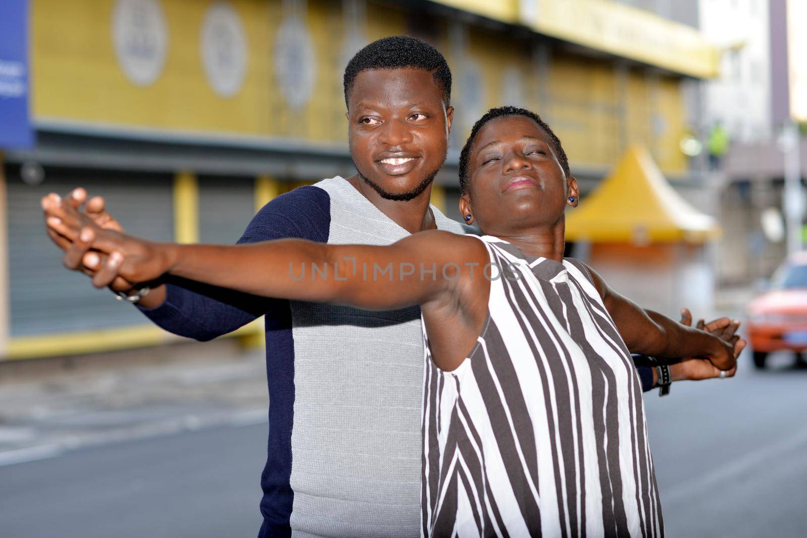 young couple standing in the intertwined street smiling.