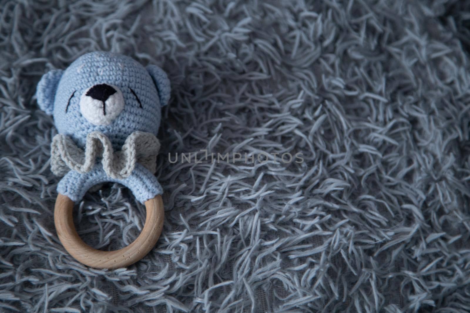 A toy for a baby in the form of a knitted bear cub lies on a fluffy gray background. High quality photo