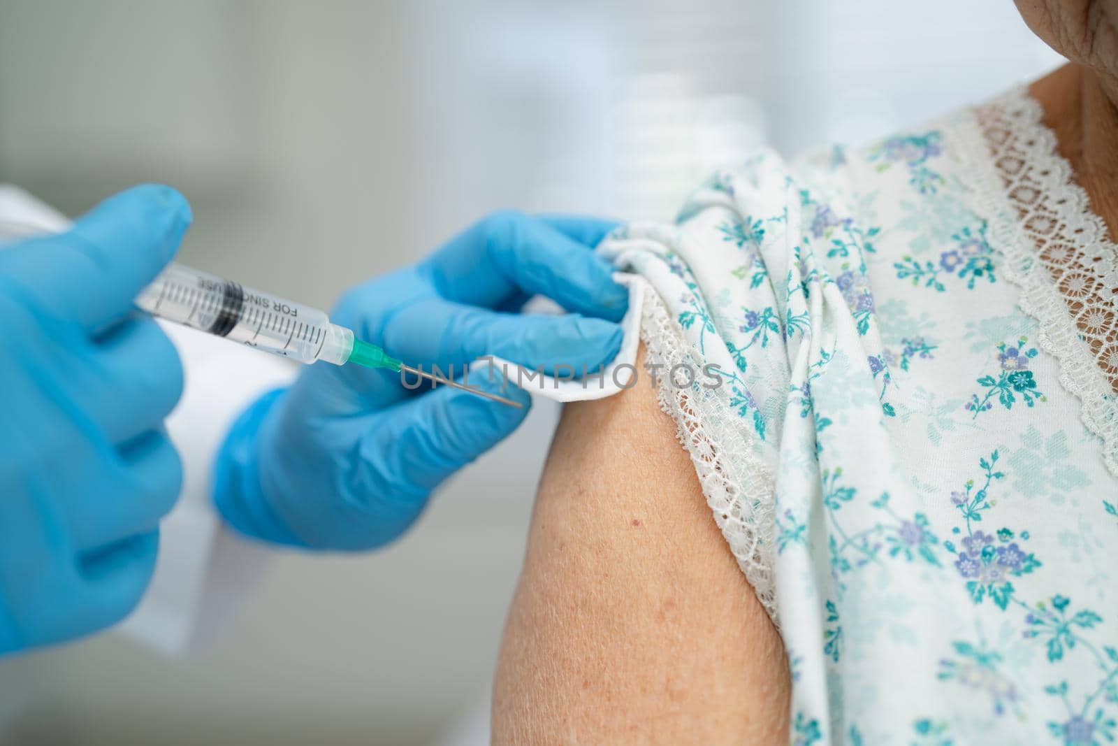 Elderly Asian senior woman wearing face mask getting covid-19 or coronavirus vaccine by doctor make injection.