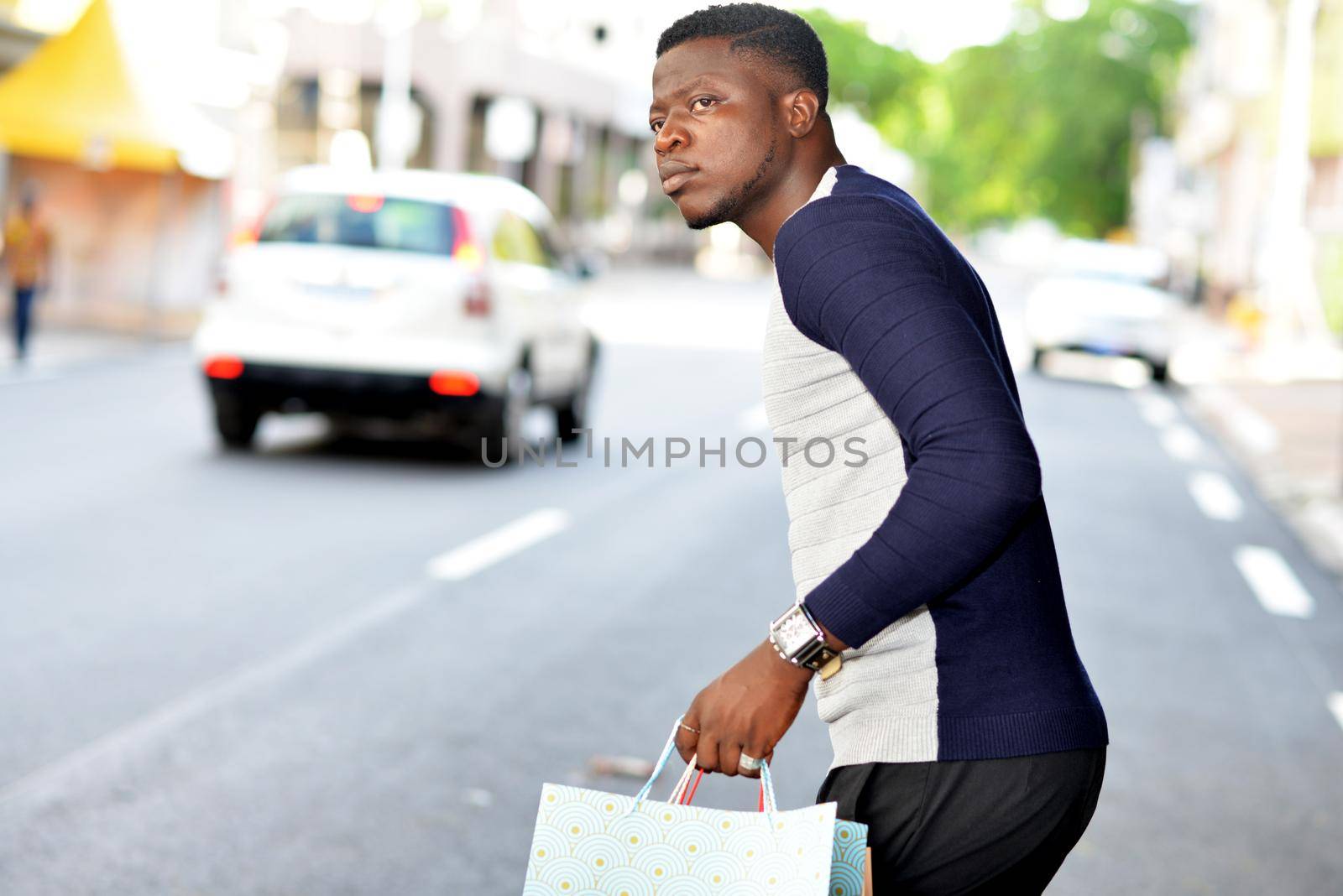 young african man standing in polo on the street and looking at the camera.
