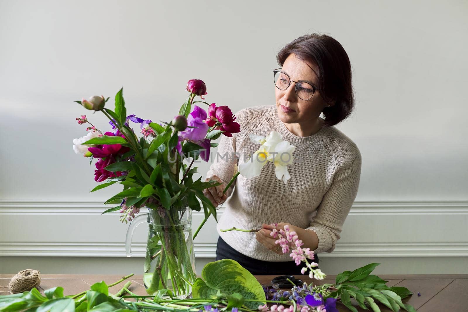 Mature woman at home with spring flowers by VH-studio