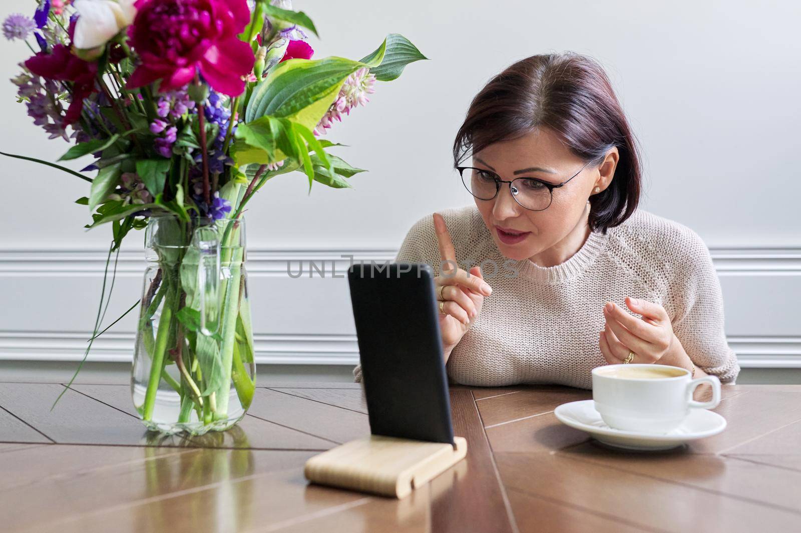 Serious mature woman talking looking at smartphone screen by VH-studio