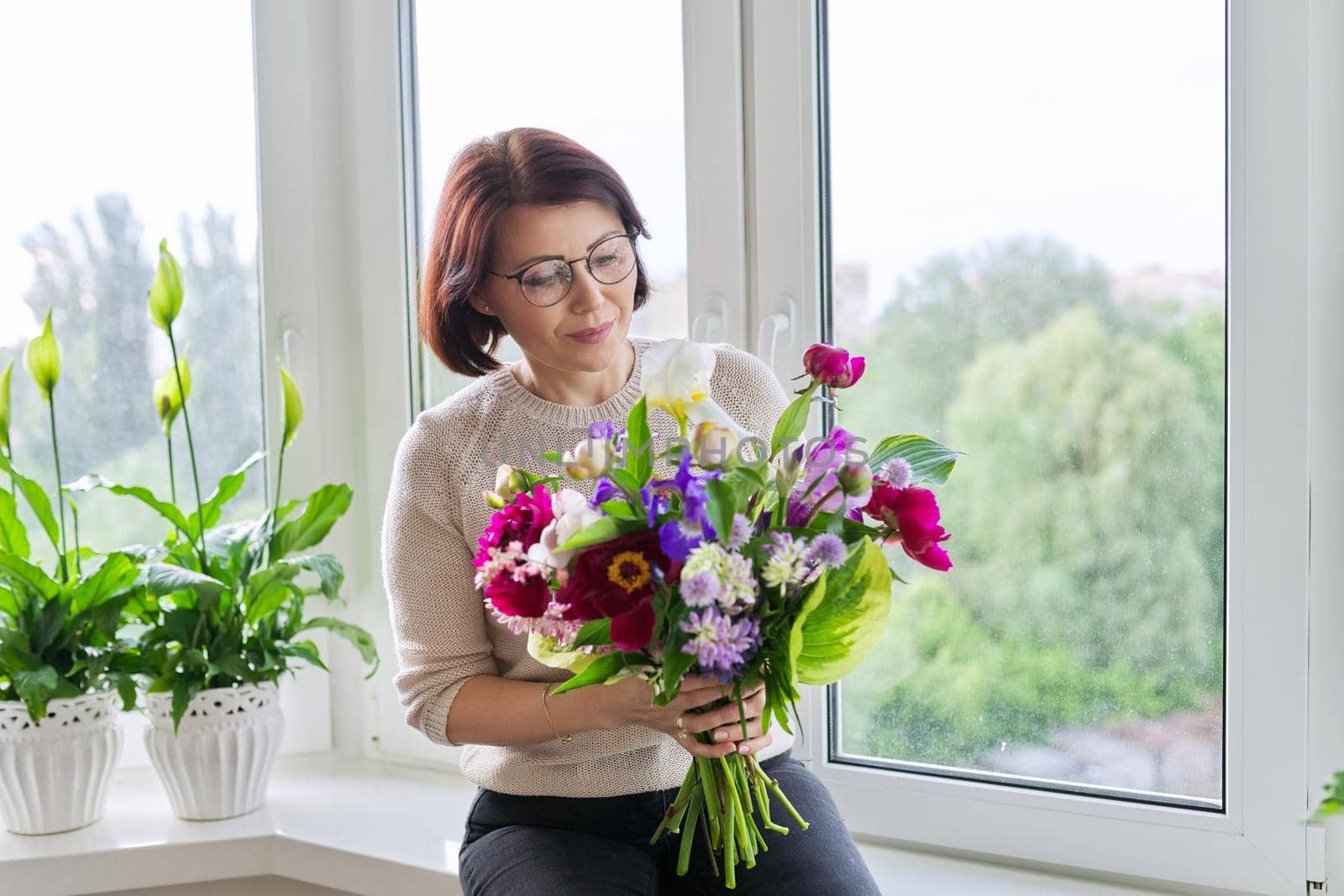 Portrait of beautiful mature woman with bouquet at home by VH-studio