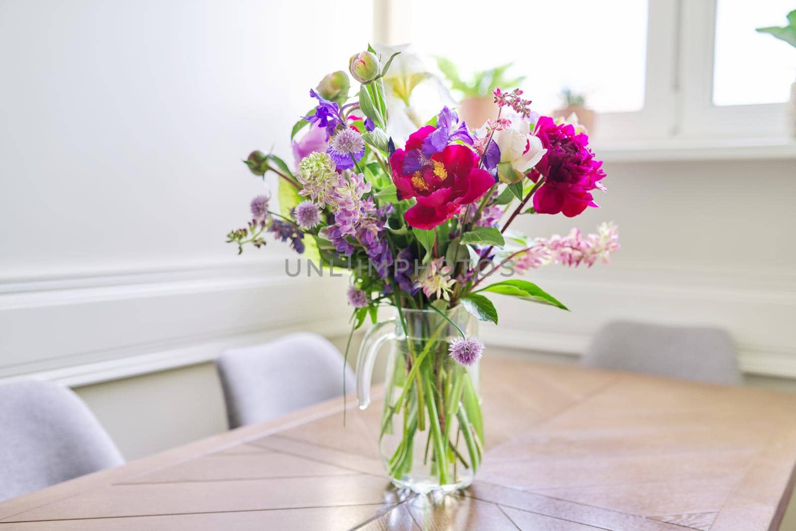 Bouquet of bright flowers on the table in jug by VH-studio