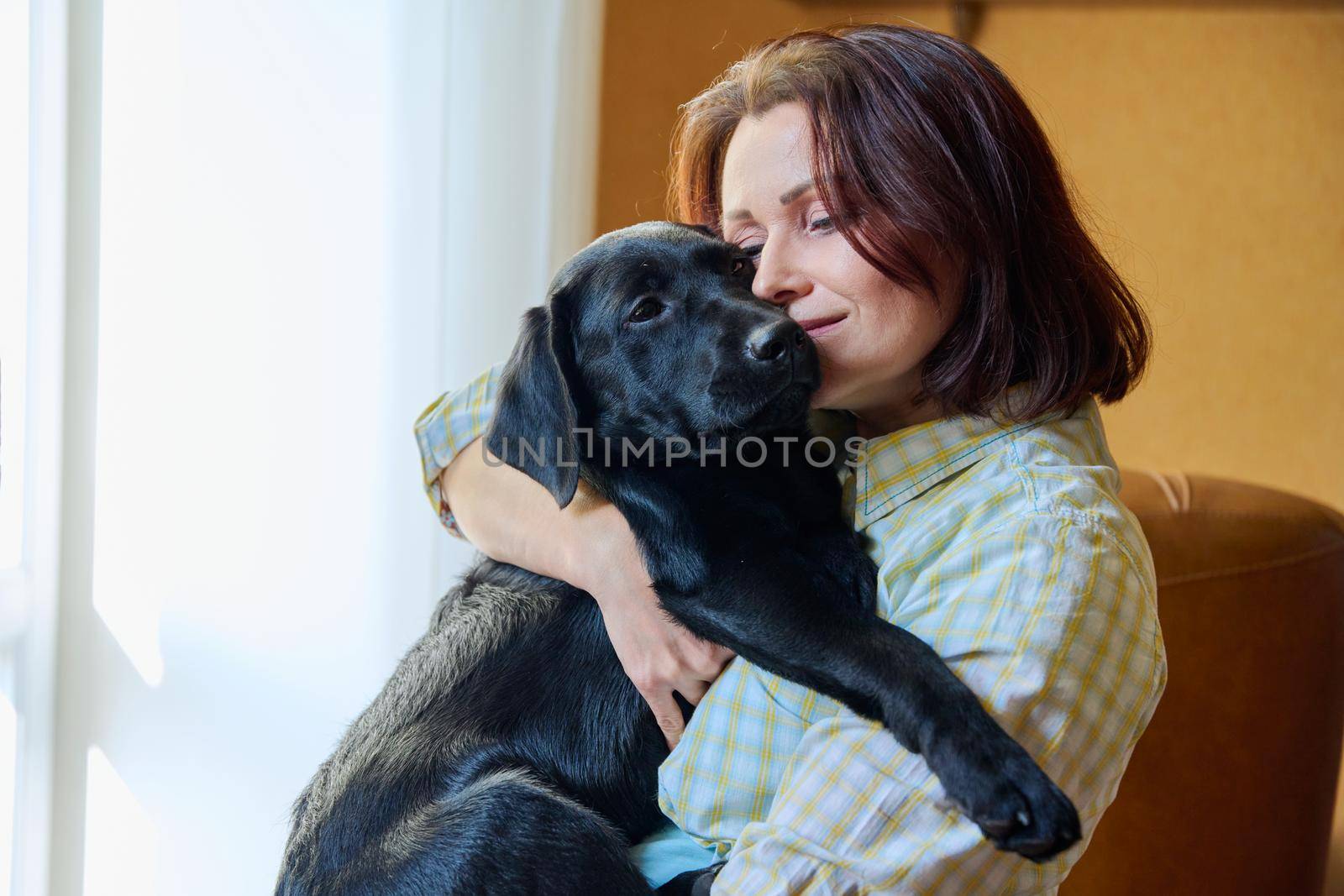 Portrait of middle aged woman and black labrador puppy dog by VH-studio