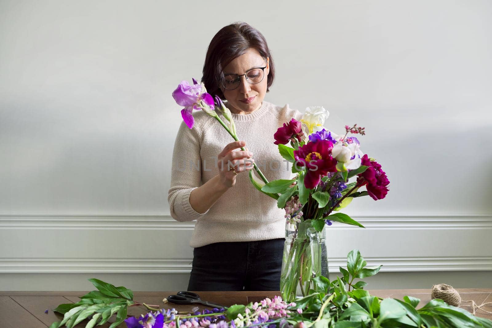 Mature woman at home with spring flowers by VH-studio