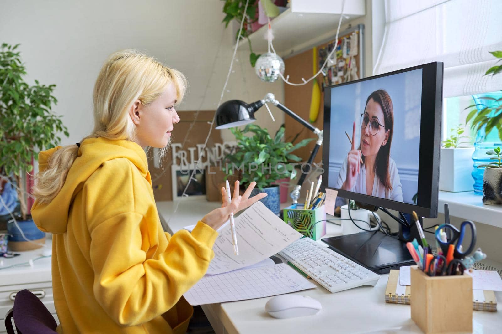 Girl teenager studies sitting at home using computer, talking online with female teacher by VH-studio