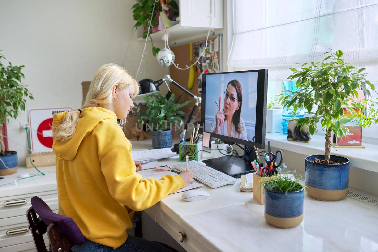 Online learning, e-education, virtual lesson. Girl teenager studies sitting at home using computer, talking online with female teacher, video consultation conference. Modern technologies in education