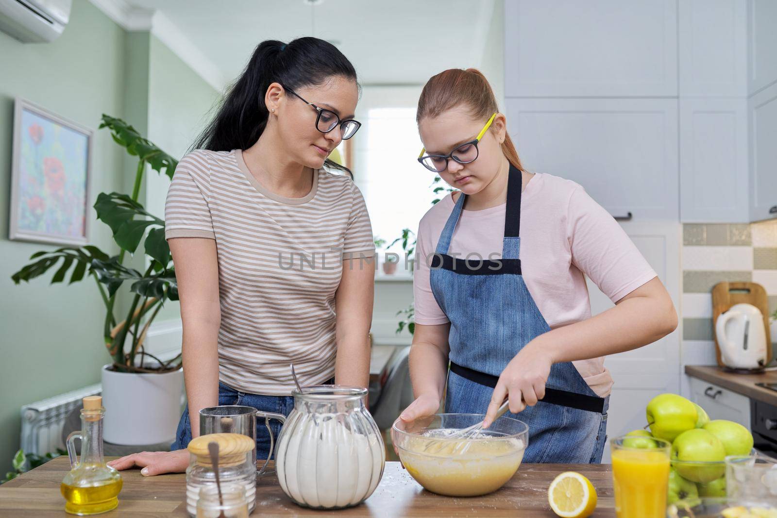 Mom and daughter 12, 13 years old cook together apple pie, mother teaches girl cooking, parent-teen communication, lifestyle, eat at home concept