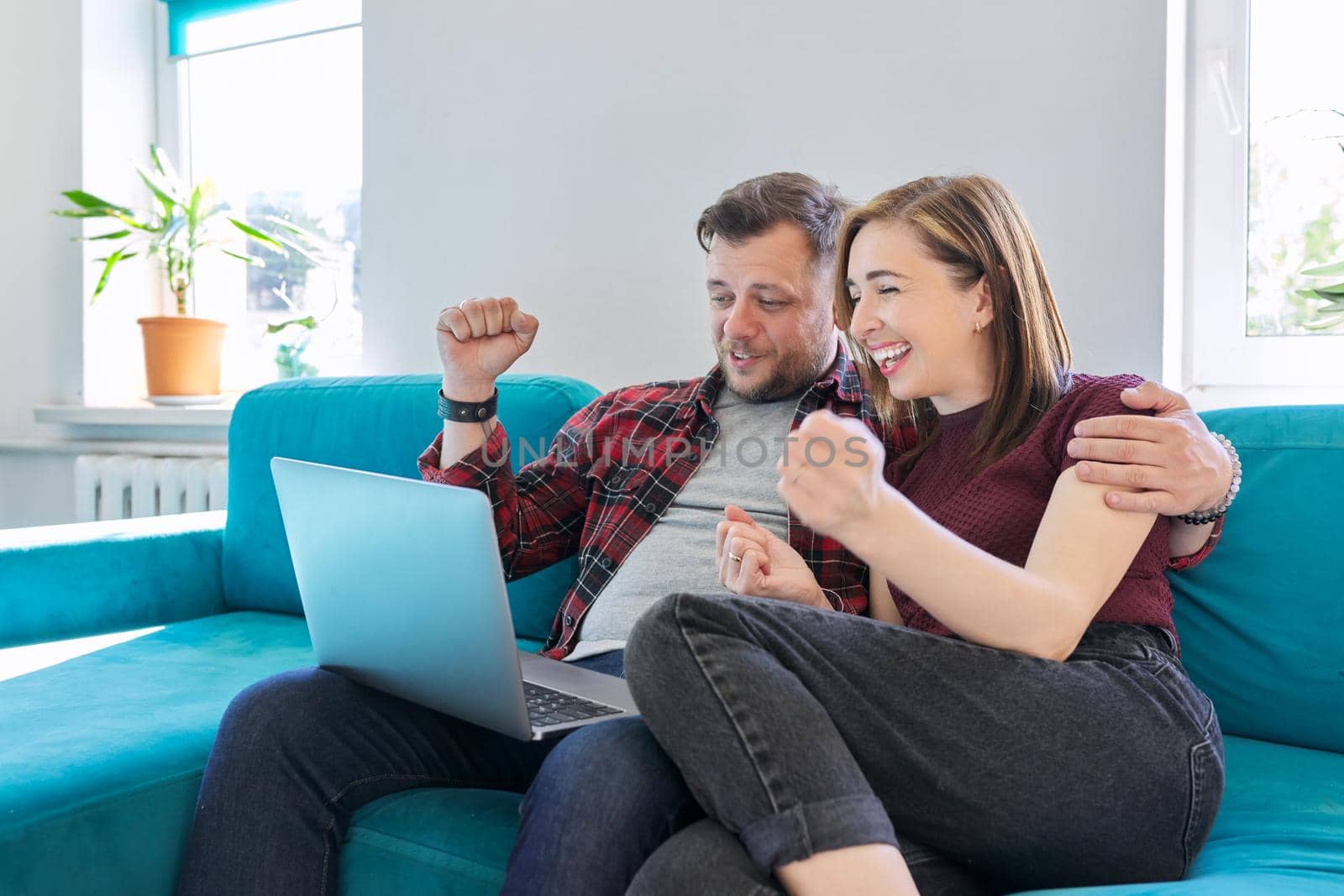 Luck, happiness, joy, victory, won, happy emotional middle aged couple looking in laptop monitor sitting at home on sofa in living room