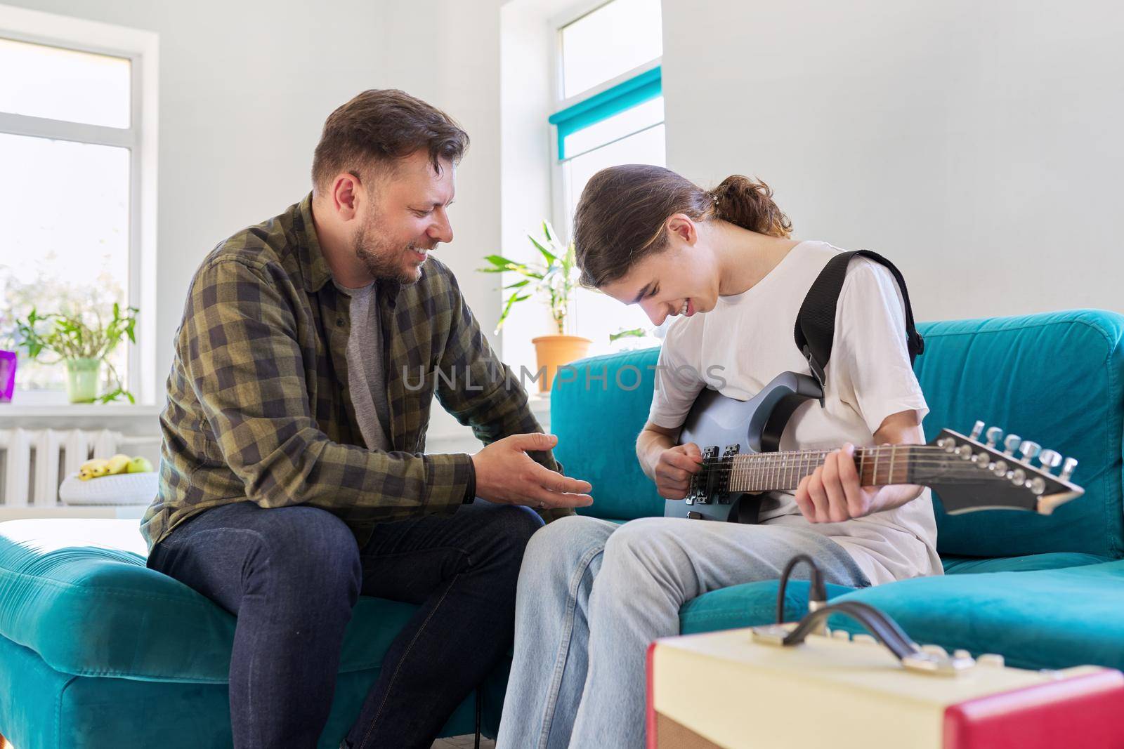 Father teaches his teenage son to play the electric guitar by VH-studio